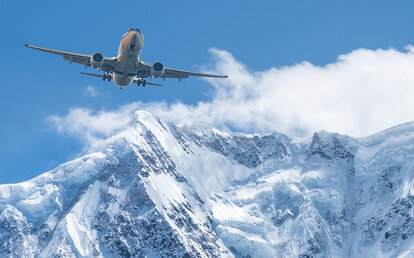 Flugzeug über schneebedeckten Bergen – Sonderpreise für Flugtickets